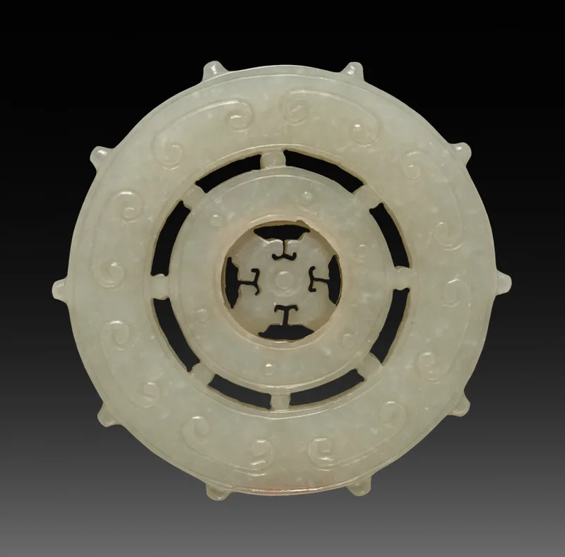 White jade ornament carved as a spoked wheel with a central hub