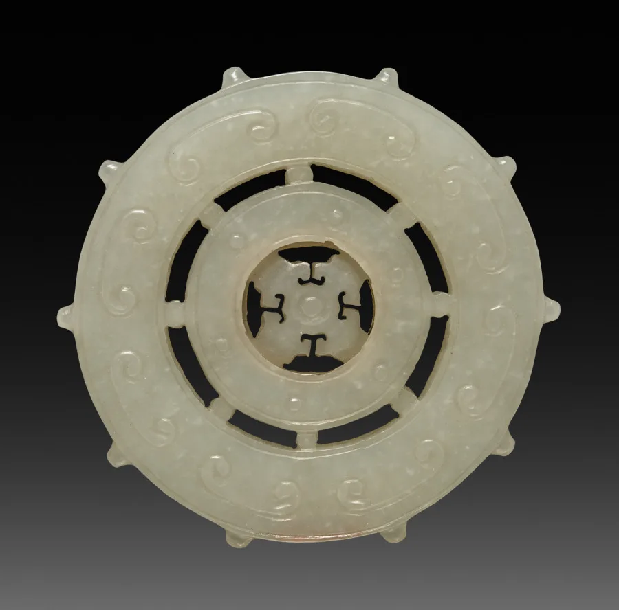 White jade ornament carved as a spoked wheel with a central hub