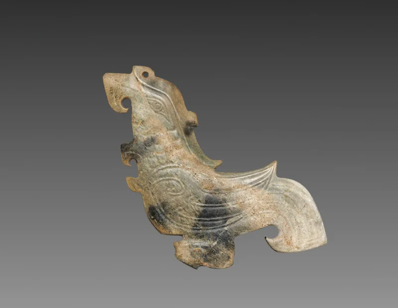 Flat nephrite plaque carved in the profile silhouette of a bird, with incised feather detail
