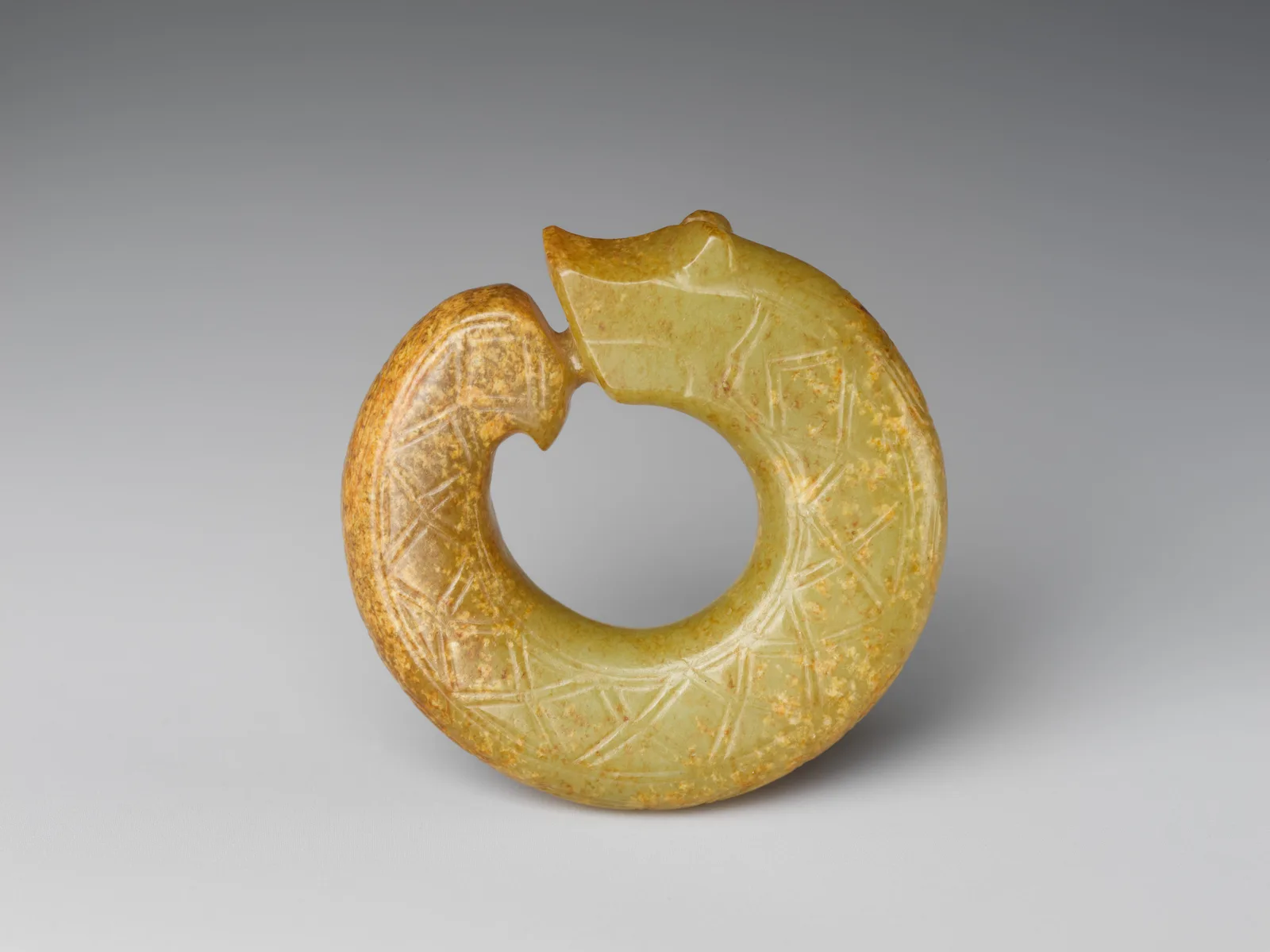 Jade (nephrite) pendant, in the shape of a coiling dragon, shang and zhou dynasties, 4.4 cm across.